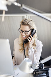 Smiling blond woman in office on the phone - PESF000070