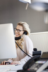 Lächelnde blonde Frau im Büro am Telefon - PESF000073