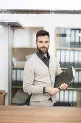 Mann im Büro hält Aktenordner - PESF000078