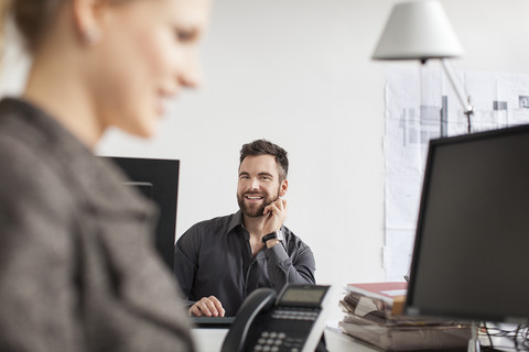 Mann im Büro schaut Frau an, lizenzfreies Stockfoto