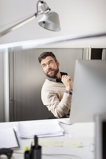 Mann im Büro sitzt am Schreibtisch - PESF000094