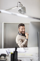 Happy man in office sitting at desk - PESF000097