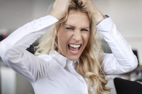 Blonde Frau im Büro, die sich die Haare rauft - PESF000104