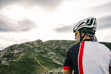 Spain, Tarragona, Mountain biker in extreme terrain, looking at landscape - JRFF000011