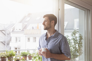 Lächelnder Mann schaut aus dem Fenster - RBF003497