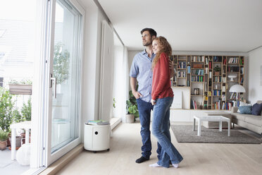 Couple in living room looking out of window - RBF003554