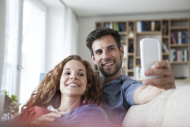 Relaxed couple at home on couch looking on cell phone - RBF003559