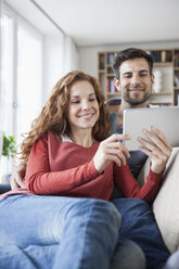 Relaxed couple at home on couch using digital tablet - RBF003537