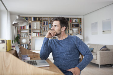 Man at home looking away from laptop - RBF003553