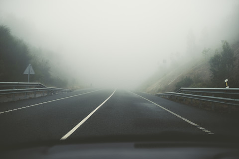 Spanien, Blick vom Auto auf die leere Straße bei Nebel, lizenzfreies Stockfoto