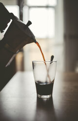 Man pouring espresso from can into a glass - RAEF000384