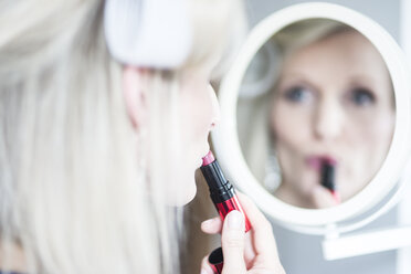 Blonde Frau mit Lockenwicklern trägt Lippenstift auf - CHPF000162