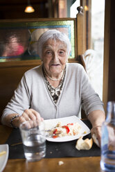 Porträt einer älteren Frau beim Essen in einem Restaurant - RAEF000373