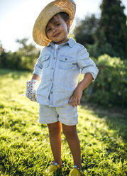 Porträt eines lächelnden kleinen Mädchens mit Strohhut, das in einem Garten steht - MGOF000513