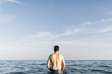 Rückenansicht eines jungen Mannes, der im Meer steht und in die Ferne schaut - JRFF000015