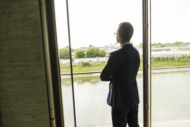 Junger Geschäftsmann schaut aus dem Fenster - UUF005437