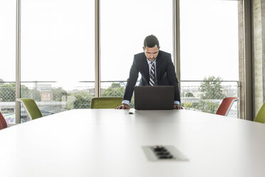 Young businessman in conference room looking at laptop - UUF005415