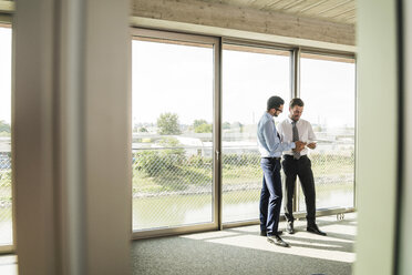 Two businessmen with digital tablet at the window - UUF005440