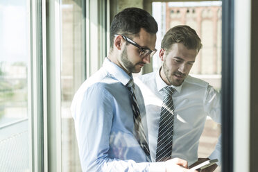 Two young businessmen with smartphone at the window - UUF005451