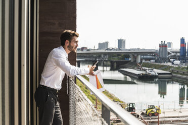 Young businessman standing on balcony looking at view - UUF005469