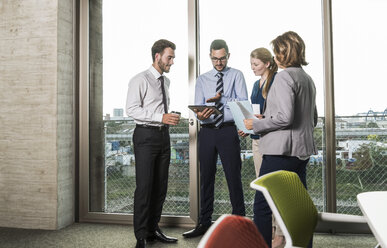 Business people with digital tablet and documents talking at the window - UUF005506