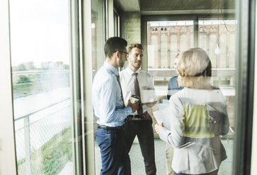 Business people with documents talking at the window - UUF005511