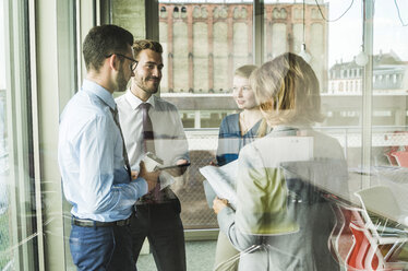 Business people with documents talking at the window - UUF005512