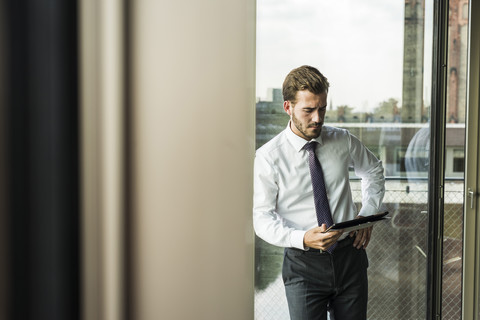 Junger Geschäftsmann mit Blick auf ein digitales Tablet, lizenzfreies Stockfoto