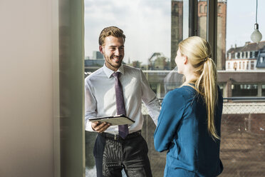 Smiling young businesswoman and businessman with digital tablet - UUF005526