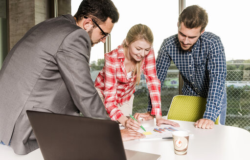 Drei junge Leute arbeiten in einem Konferenzraum an einem Diagramm - UUF005554