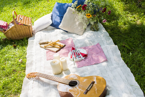 Picknickdecke mit Gitarre, Kerzen und Kissen auf einer Wiese - KSWF001561