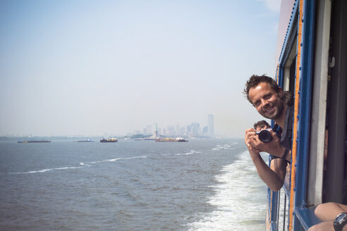 USA, New York City, Tourist mit Kamera auf der Staten Island Ferry mit Blick auf die Skyline von Manhattan und den East River - ONF000921