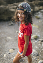 Spanien, Gijon, Porträt eines lächelnden kleinen Mädchens am felsigen Strand - MGOF000560