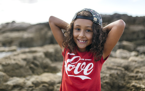 Spain, Gijon, portrait of smiling little girl at rocky coast stock photo