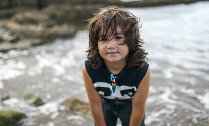 Spain, Gijon, portrait of little boy with brown hair standing at seafront - MGOF000541