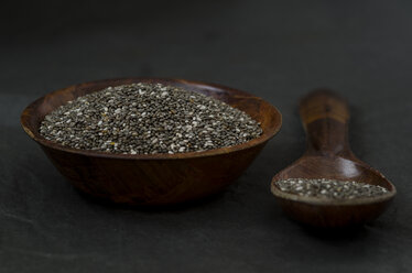 Wooden bowl and spoon of chia seeds on dark ground - ODF001225