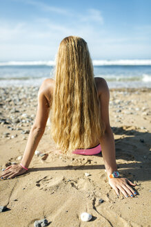 Rückenansicht einer blonden jungen Frau, die am Strand sitzt - MGOF000567