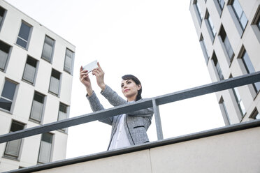 Businesswoman taking selfie with smart phone - FMKYF000619