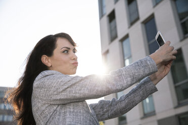 Businesswoman taking selfie with smart phone - FMKYF000628