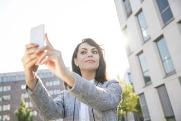 Businesswoman taking selfie with smart phone - FMKYF000620