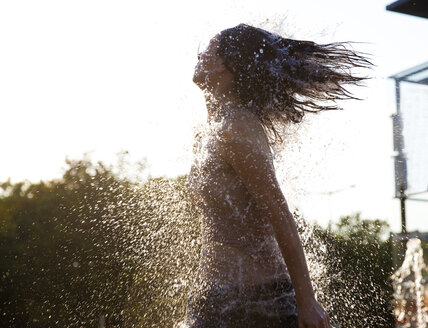 Woman running through fountain splashing water drops - FMKYF000624