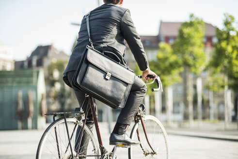 Junger Geschäftsmann fährt Fahrrad - UUF005574