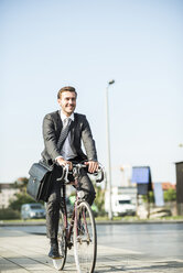 Junger Geschäftsmann fährt Fahrrad - UUF005575