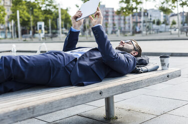 Young businessman lying on bench, working - UUF005586