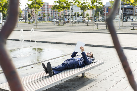 Junger Geschäftsmann auf einer Bank liegend, arbeitend, lizenzfreies Stockfoto