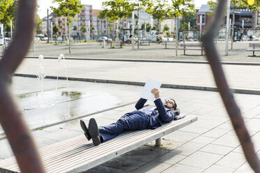 Young businessman lying on bench, working - UUF005589