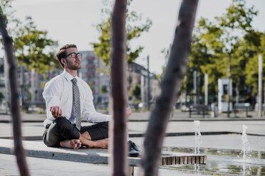 Young businessman meditating on bench - UUF005598