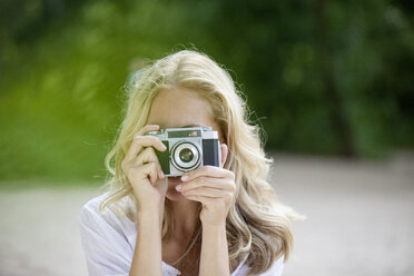 Blonde Frau, die ein Foto mit einer alten Kamera macht - FMKF002065