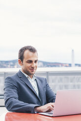 Young businessman working outside the office, laptop - BZF000230