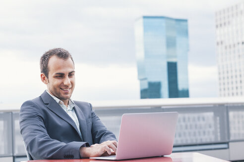 Young businessman working outside the office, laptop - BZF000219